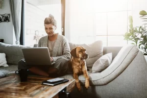 Une freelance qui travaille sur son canapé avec son chien