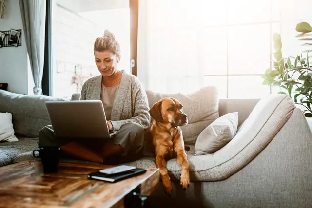 une freelance et son chien qui travaille sur son canapé
