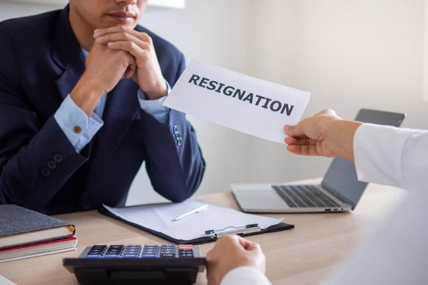 une pro qui donne un papier a un autre avec marqué resignation dessus