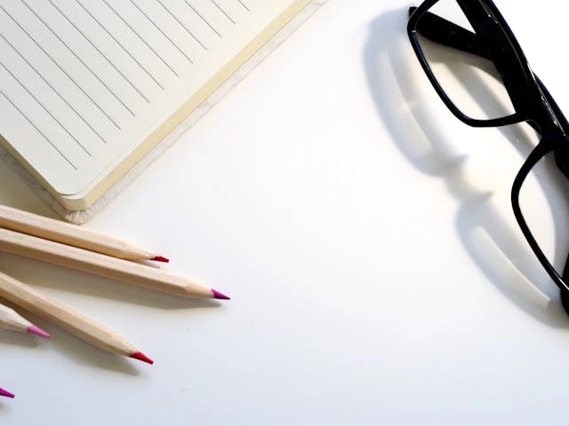 des crayons et du papiers avec une paire de lunette