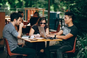3 personnes sur une terrasse de café qui travaillent devant un pc