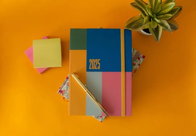 un agenda 2025 et des post it sur fond orange