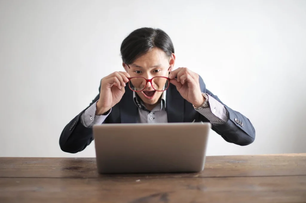 un homme devant son pc qui a l'air heureux avec ses lunettes