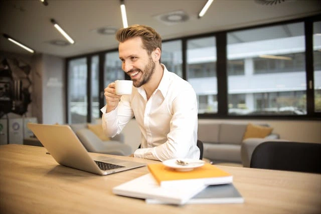 un entrepreneur devant son pc avec une tasse de café à la main