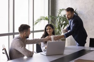2 personnes qui se serrent la main devant un pc
