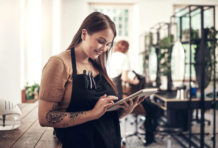 une coiffeuses en train d'utiliser une tablette