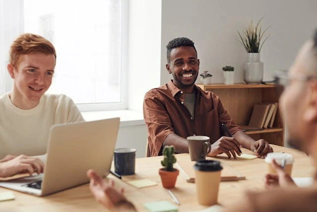 3 personnes en réunion dont 2 sont très souriantes