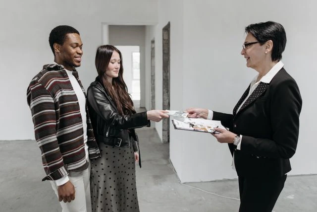 une femme agent immobilier avec 2 clients