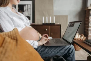 une femme enceinte devant son pc