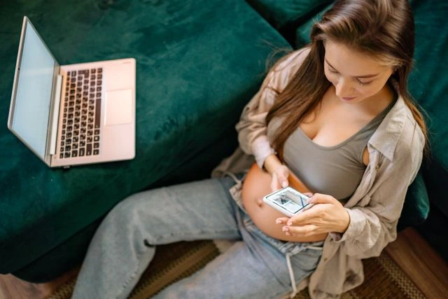 une femme enceinte avec son pc et son téléphone