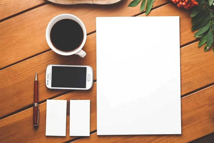 une feuille blanche avec un téléphone et un café